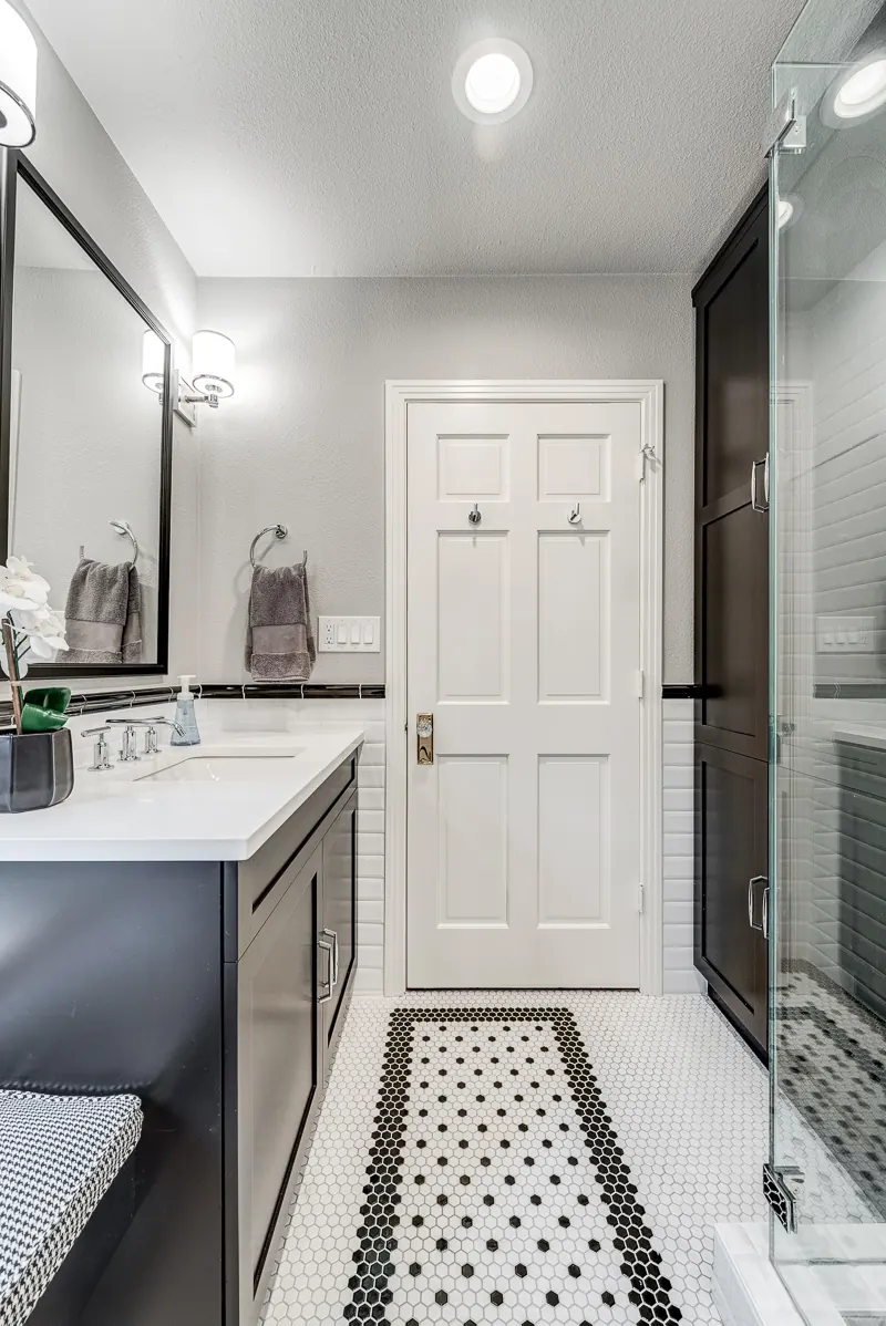 Addison bathroom remodel idea: dark vanity, framed mirror and a black and white mosaic floor