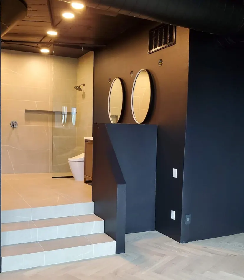 Bedford bathroom remodel idea: raised walk-in shower beside a navy wall with round gold mirrors