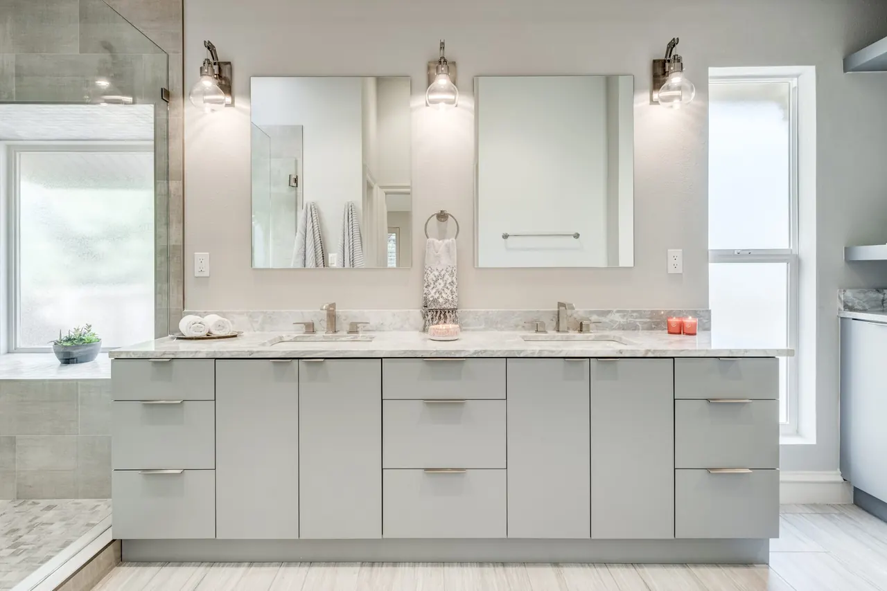Dallas bathroom remodel idea: gray double vanity with marble counters, framed mirrors and sconces