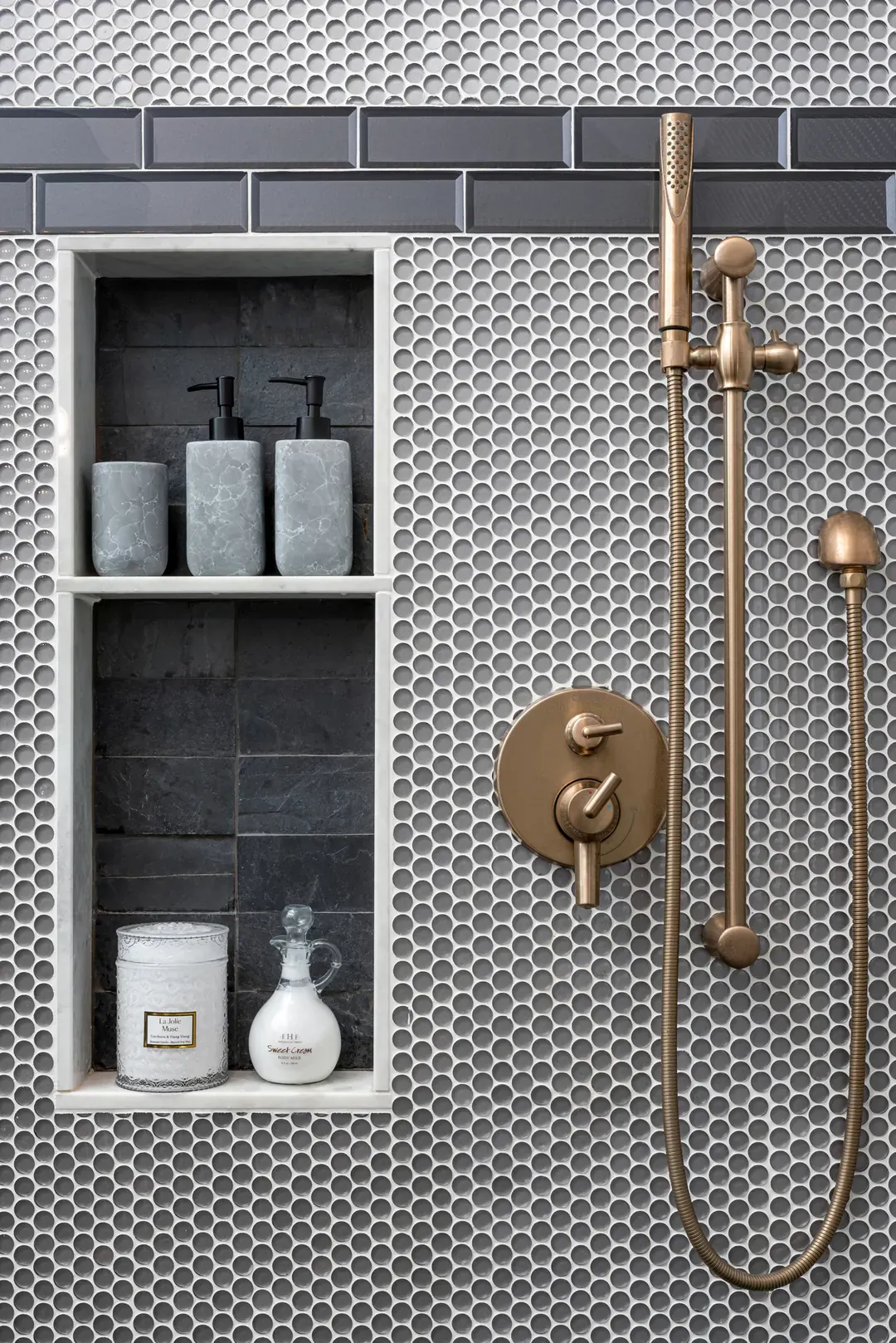 Frisco shower by Nomi in gray penny tile with a recessed niche and brushed brass fixtures