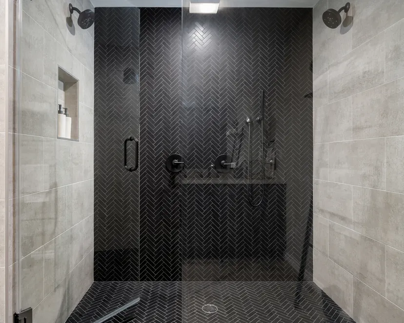 Plano bathroom remodel idea: double shower in black herringbone tile with a built-in bench