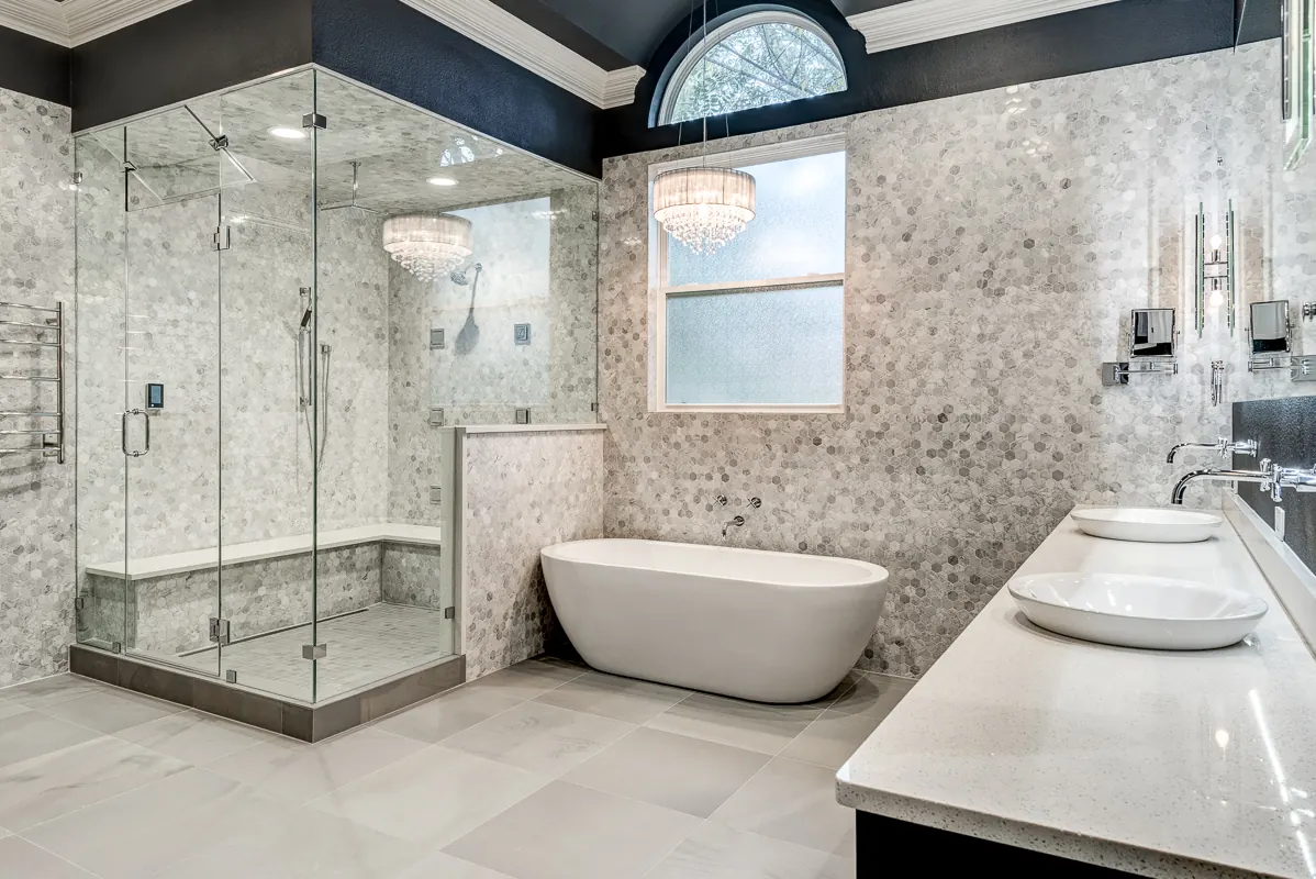 Steam shower in a Southlake master bathroom by Nomi, a sealed glass enclosure with a bench beside a freestanding tub