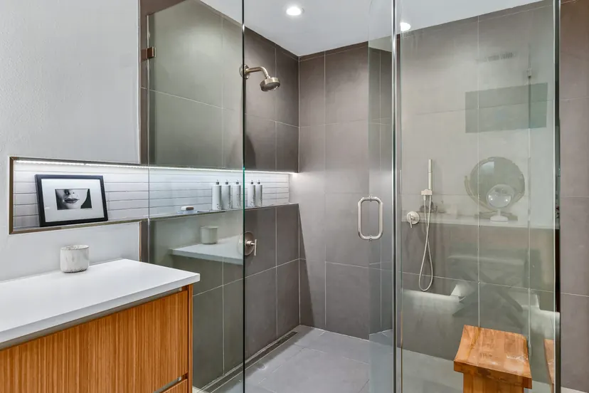 The Colony bathroom remodel idea: glass walk-in shower in dark tile with a teak bench and a wood vanity